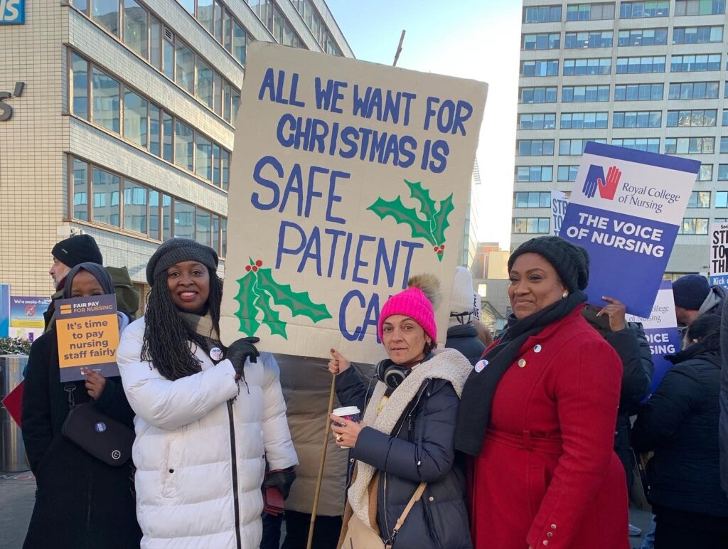 Bell and Dawn Butler stand with a striking nurse who holds a sign 'All we want for Christmas is safe patient care'.
