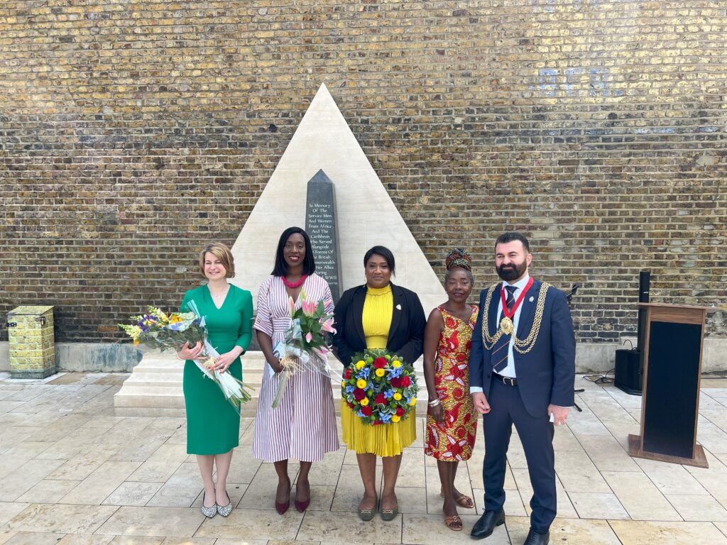 Helen Hayes MP, Florence Eshalomi MP, Bell Ribeiro-Addy MP, Cllr Sonia Winifred, Mayor Sarbaz Barznji stand in front of the African & Caribbean War Memorial. The MPs hold wreaths and flowers to lay.
