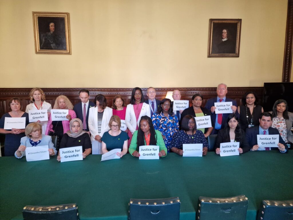 Labour MPs stand in a parliamentary room holding signs that read Justice for Grenfell