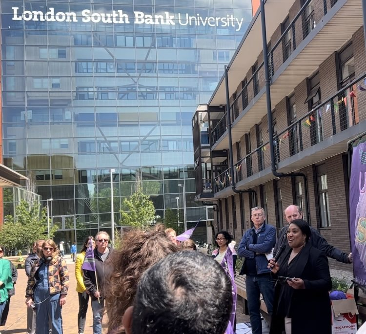 Bell speaking to a rally of people holding banners outside of South Bank University (LSBU)